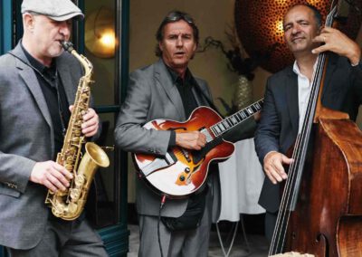 Foto 3 Musiker in Hamburg beim Empfang auf dem Süllberg. Stehen in einer Tür und spielen auf die Terrasse hinaus. Sympathische Musiker, mittleres Alter und gut gekleidet.